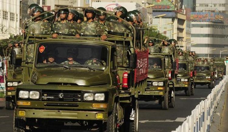 Trucks loaded with armed soldiers patrol around downtown Urumchi on July 9. (AFP/Getty Image)