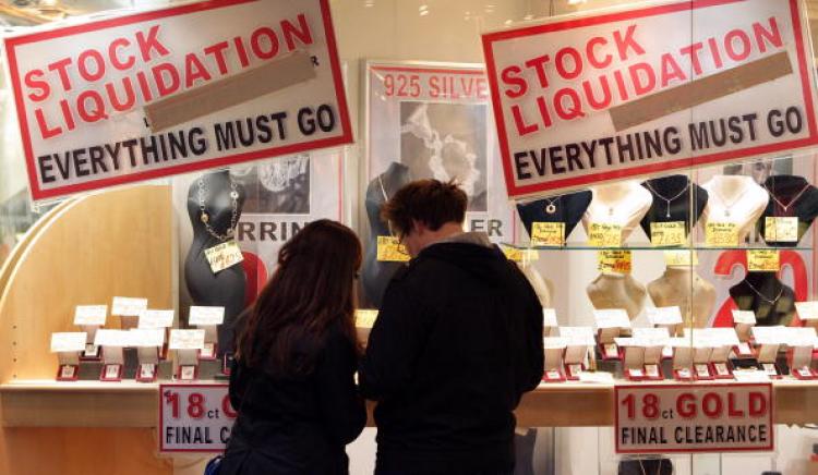 A couple look at the jewelery for sale in a shop adorned with posters advertising ' Stock Liquidation ' on Bond Street in London.  (Oli Scarff/Getty Images)