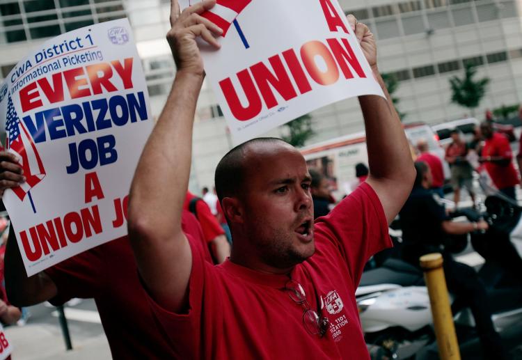 Workers march and hold up placards outside of a Verizon office last Thursday in Lower Manhattan.  (Chris Hondros/Getty Images)