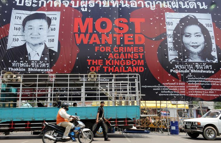 An anti-government poster depicting former Thai prime minister Thaksin Shinawatra and his wife Pojjaman in front of the United Nations office near Government House in Bangkok. The Thai government is seeking the extradition of former the Thai prime minister.  (Saeed Khan/Getty Images)