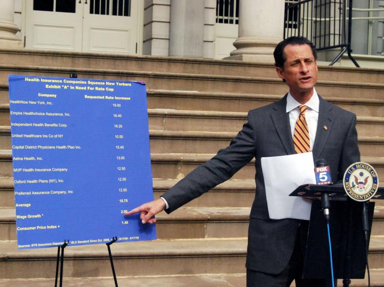 INSURANCE TRACKER: Rep. Anthony Weiner refers to a chart that compares high health insurance companies' rate increase requests and much lower wage increases at a press conference at City Hall on Sunday. (Catherine Yang/The Epoch Times)