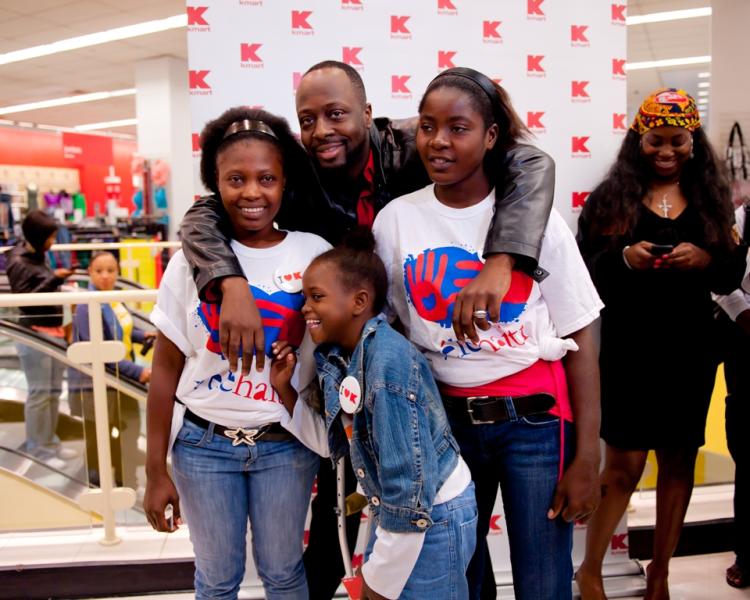 Wyclef poses with amputees Margarette, on the right, Chantal on the left and little Farah in the front as they pose for a few pictures before setting off on a shopping spree at Penn Station KMart on Tuesday.  (Aloysio Santos/The Epoch Times)