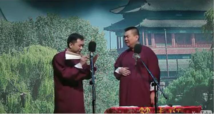 BOLD: A screen grab of the video shows Wang (L) using a traditional fan as a prop as he jokes with Zhang (R) in a performance that heavily satirized communist authorities. (The Epoch Times)