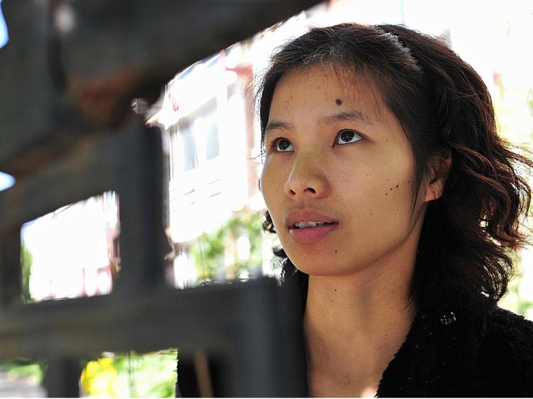 Chinese dissident Zeng Jinyan stands behind a gated compound at Bobo Freedom Village where she lives under unofficial house arrest   (Frederic J. Brown/AFP/Getty Images)