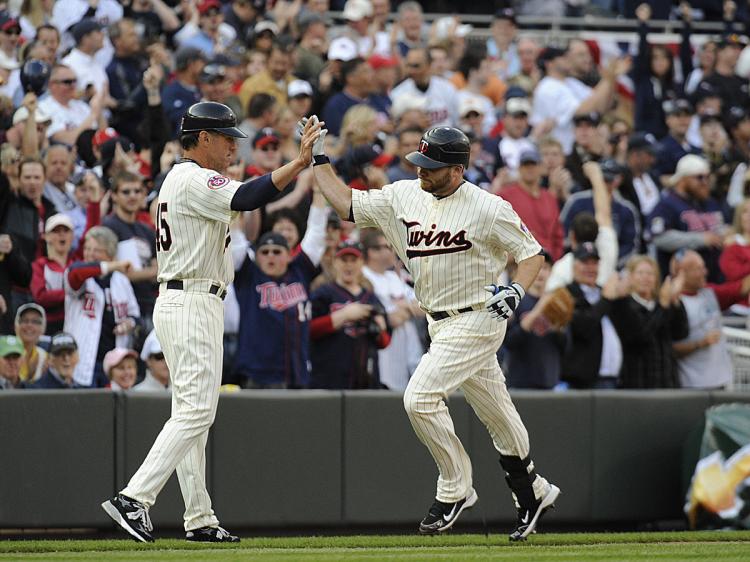 Third base coach Scott Ullger #45 and Jason Kubel #16 of the Minnesota Twins celebrate Kubel hitting the first home run at Target Field in the seventh inning against the Boston Red Sox during the Twins home opener at Target Field. (Hannah Foslien /Getty Images)
