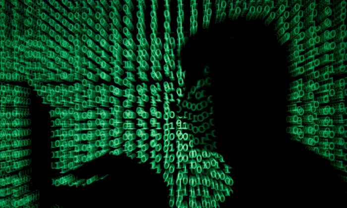 A man holds a laptop computer as cyber code is projected on him in this illustration picture taken on May 13, 2017. (Kacper Pempel/Reuters)