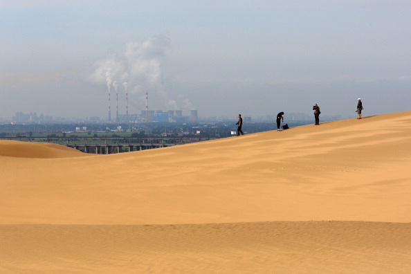 Toursits anda nas dunas perto de uma central energética no deserto de Xiangshawan em Ordos de Inner Mongolia, nesta foto do arquivo. Os mineradores de bitcoin desfrutam de taxas de eletricidade favoráveis ​​em lugares como Ordos há muito tempo (Feng Li / Getty Images)