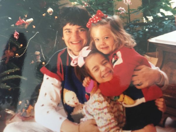 woman poses with two laughing daughters