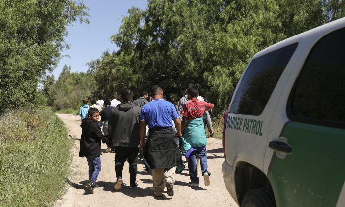 A group of illegal aliens walk up the road after crossing the Rio Grande from Mexico. Further up the road, they will be processed by Border Patrol and then board a bus bound for the Border Patrol processing facility in McAllen, Texas, on April 18, 2019. (Charlotte Cuthbertson/The Epoch Times)