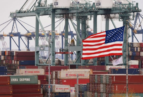 Chinese shipping containers beside a US flag at the Port of Los Angeles in Long Beach