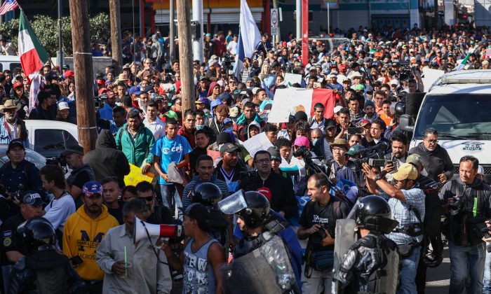 Migrants rush past riot police at the foot of a bridge leading from the migrant camp to the El Chaparral pedestrian entrance at the San Ysidro border crossing in Tijuana, Mexico, on Nov. 25, 2018. (Charlotte Cuthbertson/The Epoch Times)