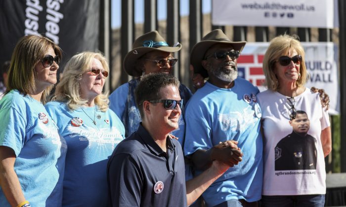 Brian Kolfage, founder of We Build the Wall, with a group of Angel parents, whose children have been killed by illegal aliens, in front of the new half-mile section of border fence at Sunland Park, N.M., on May 30, 2019. (Charlotte Cuthbertson/The Epoch Times)