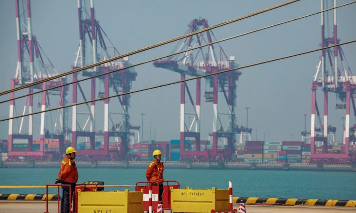Two staff members stand at a port in Qingdao in China's eastern Shandong Province on April 17, 2019. (STR/AFP/Getty Images)