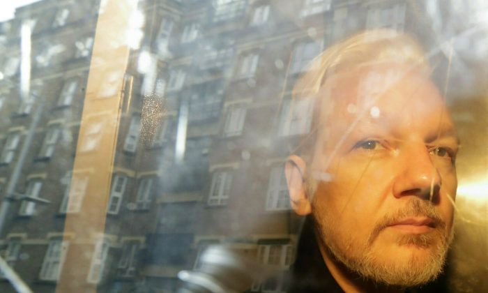 Buildings are reflected in the window as WikiLeaks founder Julian Assange is taken from court, where he appeared on charges of jumping British bail seven years ago, in London on May 1, 2019. (Matt Dunham/AP)