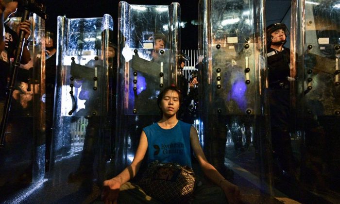 Lam Ka Lo (C) meditates in front of a line of riot police standing guard with their shields outside the government headquarters in Hong Kong early on June 12, 2019. (Anthony Wallace/AFP/Getty Images)