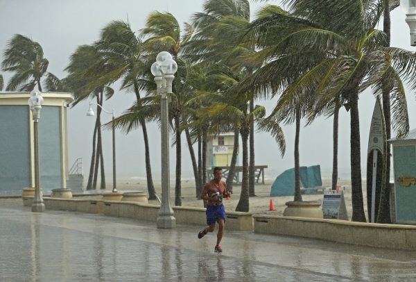 A beachgoer runs under the rain