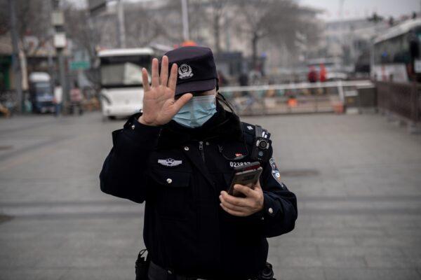 A police officer gestures to a journalist not to photograph in Beijing, China, on March 5, 2021. (NICOLAS ASFOURI/AFP via Getty Images)