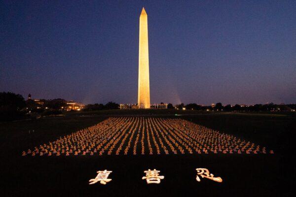 Falun Gong practitioners at candlelight vigil remembering victims of the 22 years of persecution in China at the Washington Monument on July 16, 2021. The characters for "Truthfulness, Compassion, Tolerance," the principles taught by the spiritual practice appear at the front. (Larry Dye/The Epoch Times)