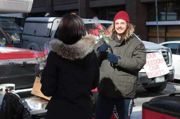 A protester beams happily after receiving a Valentine's Day rose from a woman handing out the flowers on Feb. 14, 2022. (Richard Moore/The Epoch Times)