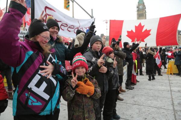Families join the protest in the center of Ottawa after police distributed arrest notices to truckers and their supporters occupying Wellington St and the Parliament Hill area. (Richard Moore/The Epoch Times)