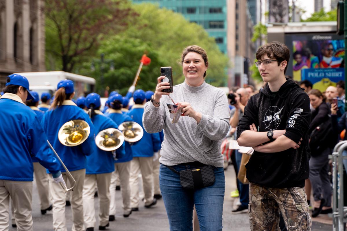 Pedestrians watch as Falun Gong practitioners take part in a parade marking the 30th anniversary of its introduction to the public, in Manhattan, New York, on May 13, 2022. (Samira Bouaou/The Epoch Times)