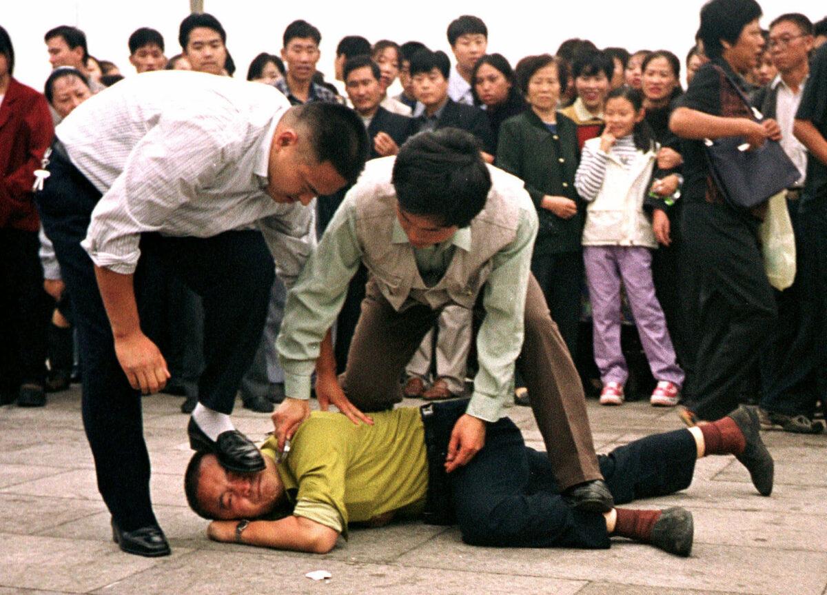 Two plainclothes police officers arrest a Falun Gong practitioner at Tiananmen Square in Beijing, on Dec. 31, 2000. (AP Photo/Chien-min Chung)