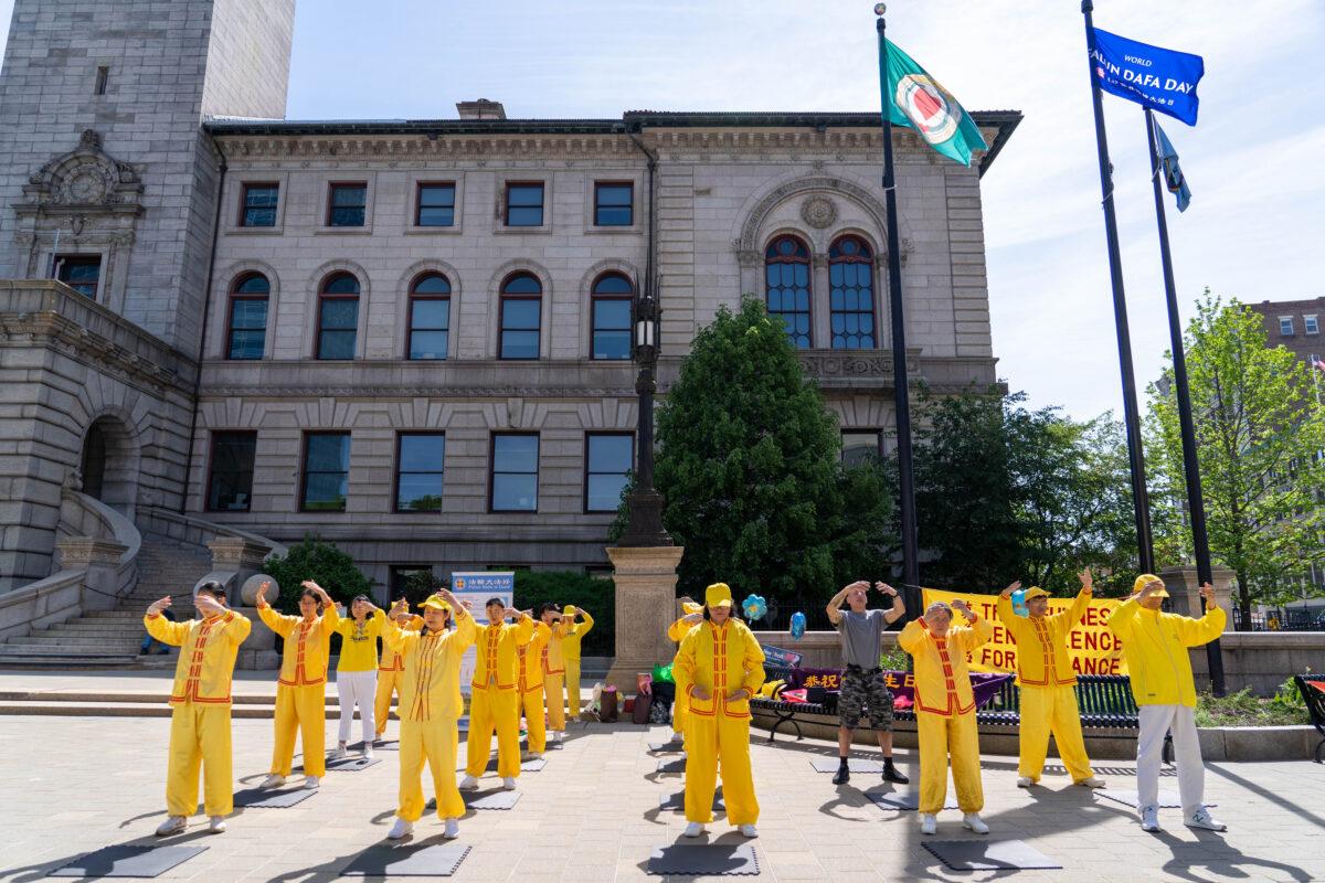 Falun Gong practitioners do group exercises to commemorate World Falun Dafa Day outside City Hall in Worcester, Mass., on May 13, 2023. (Learner Liu/The Epoch Times)